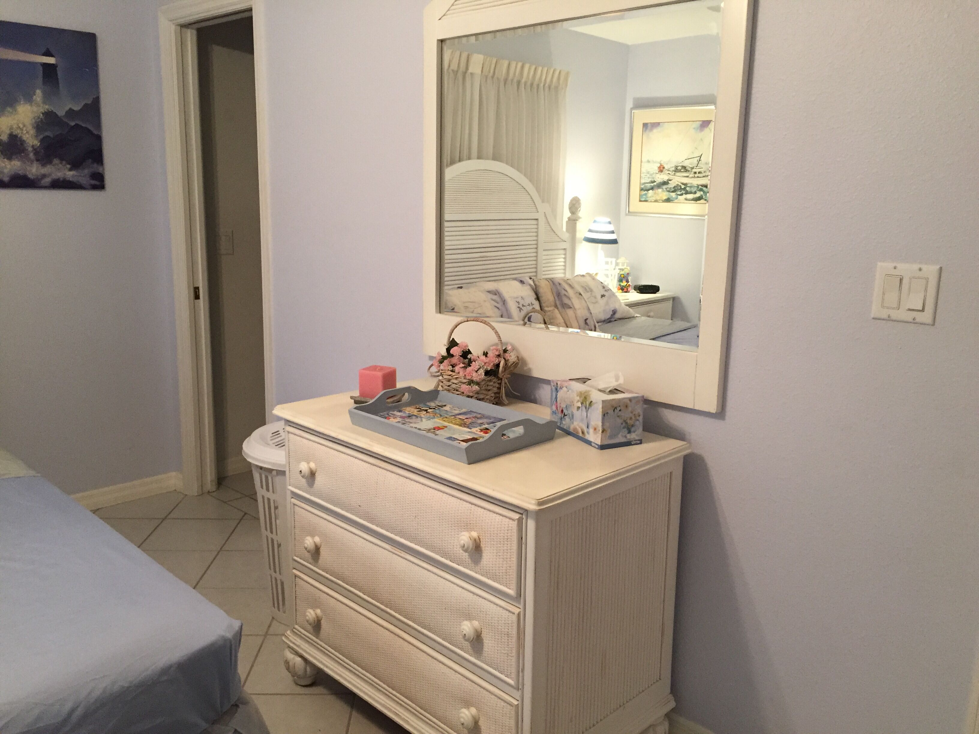 A bedroom with a dresser, a mirror, a bed, and a door.