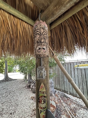 Enjoy the tranquil ambiance of this outdoor space, where a carved tiki face adorns a post near a convenient electrical outlet.