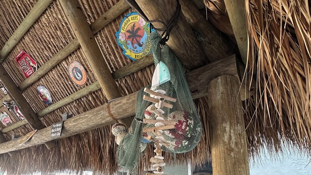 A thatched roof structure with a wooden beam and a decorative hanging ornament. - Enjoy a Fun in the Sun getaway 3 Bedroom House, Tiki Hut, Boat Ramp, & Dockage! (Key Largo)