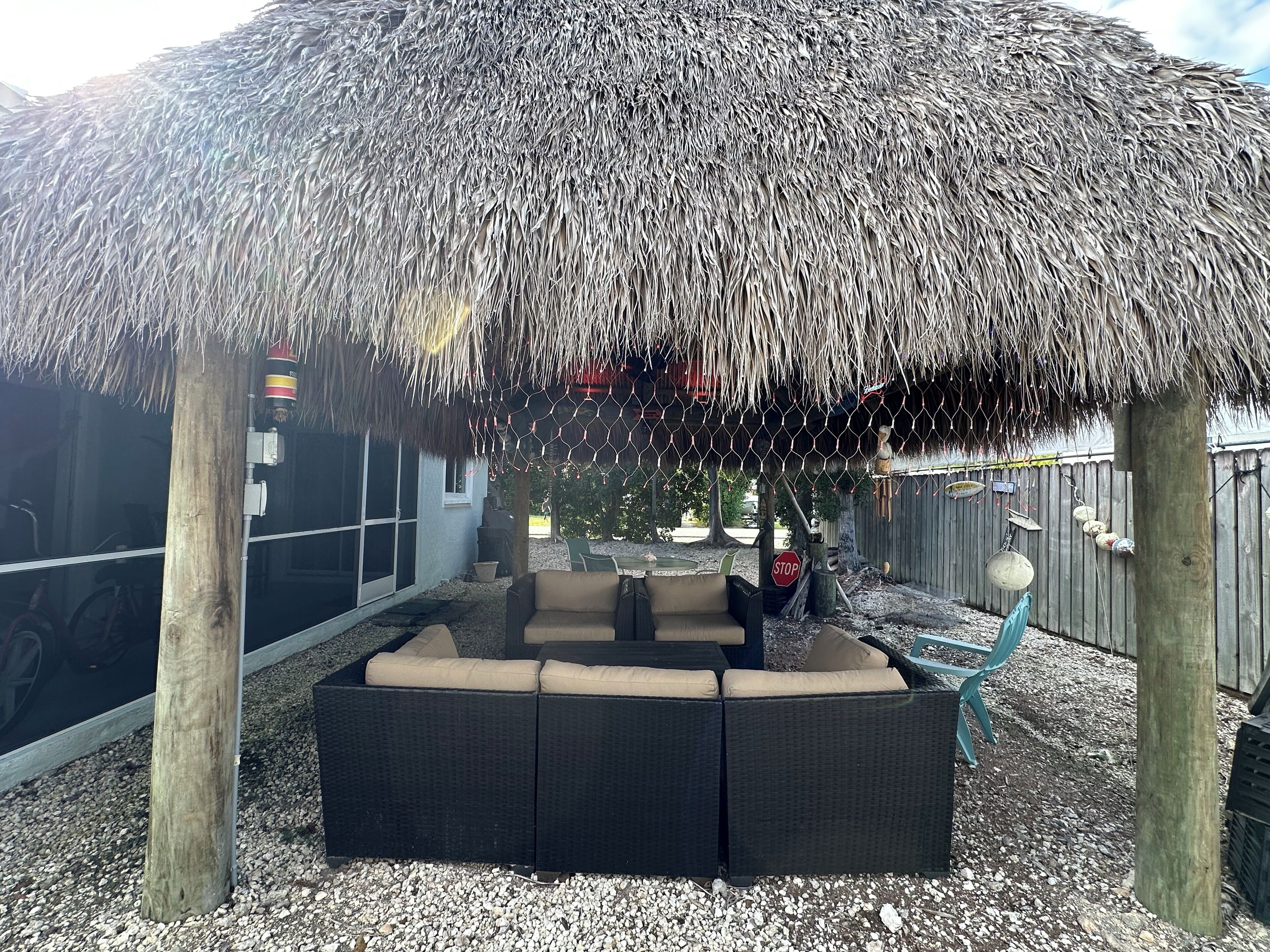 A thatched-roof outdoor seating area with a sofa and cushions.
