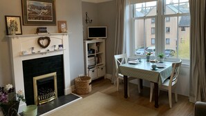 Una sala de estar acogedora con chimenea, televisión y una mesa de comedor junto a una ventana.