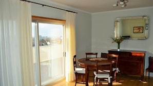 Een eetruimte met een ronde tafel, stoelen, een houten kast en een grote spiegel aan de muur.