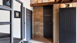 A modern interior with a staircase leading to a loft area, a brick wall, and doors labeled "Bedroom" and "Bathroom". - Beautifull loft in the hearth of Rome - A wonderful loft in the heart of Rome. (Roma)