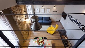 A modern interior with a stone wall, a blue sofa, a yellow chair, and a table with a floral centerpiece. - Beautifull loft in the hearth of Rome - A wonderful loft in the heart of Rome. (Roma)