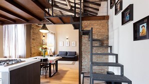 A modern kitchen with a central island, a dining area with a table and chairs, a staircase, and a living room with a sofa and a fireplace. - Beautifull loft in the hearth of Rome - A wonderful loft in the heart of Rome. (Roma)