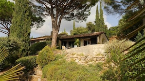 Una villa con un muro de piedra, mobiliario exterior y vistas a los árboles circundantes.