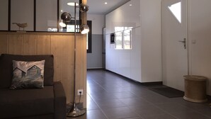 Ein modernes Wohnzimmer mit einer Couch, einer Stehlampe und Blick in die Küche.