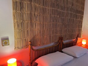 A room with a bed, a woven headboard, a wall-mounted light, and a small wall decoration. - Directly on the beach. 6 beds in villa with private access to the sea (Scala di Furno)