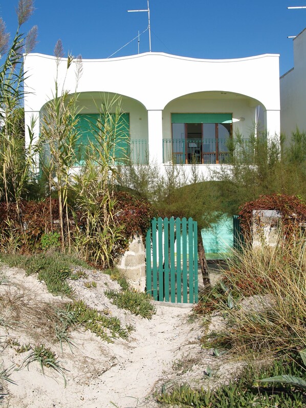A white building with green shutters and a gated entrance.