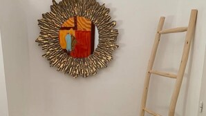 Un coin avec un banc blanc, une échelle en bois et un élément décoratif mural.