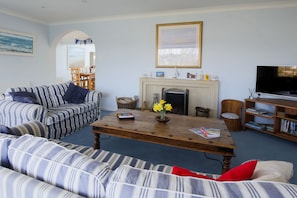 A living room with striped sofas, a wooden coffee table, a fireplace, a television, and a bookshelf.