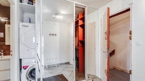 Een wasserette met een Bosch wasmachine, een droogrek en een klein strijkhoekje.