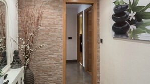 A hallway with a stone wall, a wooden door, and a painting of stones and flowers.