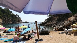 A beach with umbrellas, people, and boats.