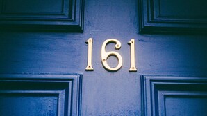 Eine blaue Tür mit der Nummer 161 und einem Messingklopfer.