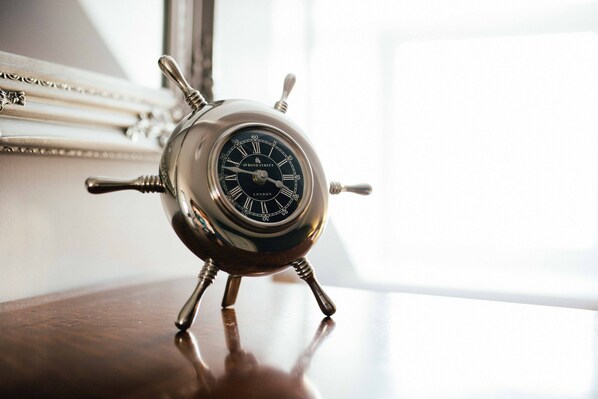A vintage-style alarm clock with Roman numerals and a brand name on its face, placed on a wooden surface.