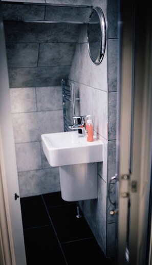 A bathroom with a white sink, a mirror, and a bottle of soap.