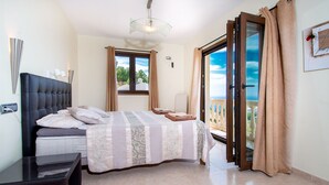 A bedroom with a bed, a nightstand, a window with curtains, and a balcony door. - Luxury modern villa with spectacular views of sea and heated private pool (La Herradura)