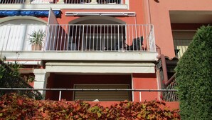 Un immeuble de deux étages doté d’un balcon, d’un garage et d’un mur rouge.