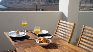 Un tavolo di legno con prodotti per la colazione e vista su una scogliera.