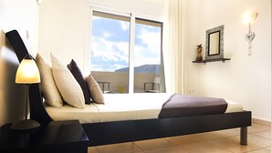 Una camera da letto moderna con un letto, un comodino, una lampada, una finestra vista e uno scaffale a parete con uno specchio.