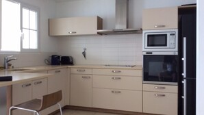 A modern kitchen with beige cabinets, a stainless steel sink, a microwave, and a built-in oven. - T3 HOUSING WITH SEA VIEW AT POINTE DU BOUT (LES TROIS ILETS)