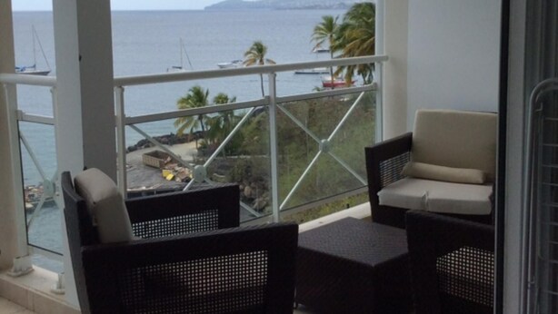A balcony with wicker furniture and a view of the sea and boats. - T3 HOUSING WITH SEA VIEW AT POINTE DU BOUT (LES TROIS ILETS)
