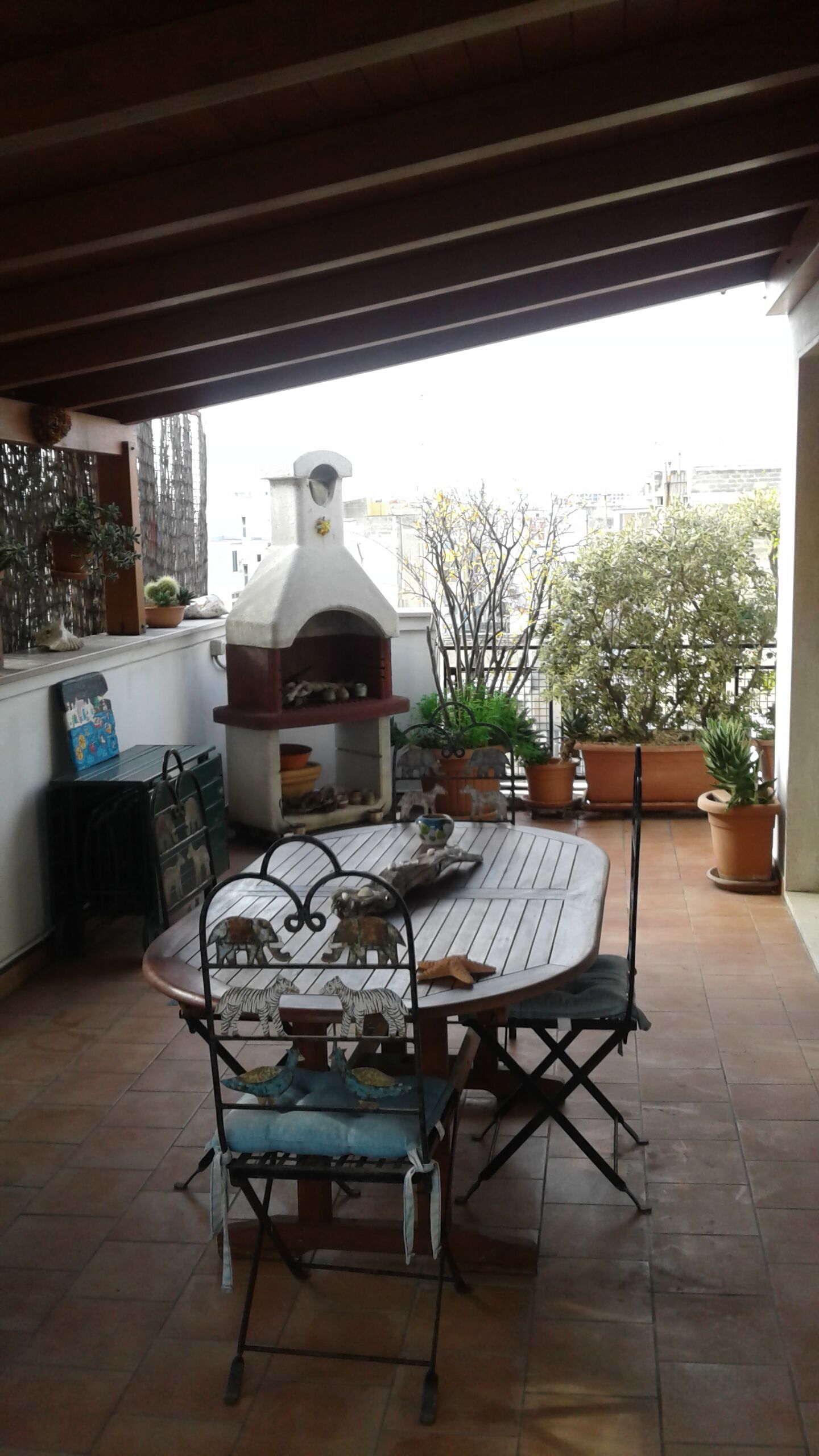Un patio al aire libre con una mesa redonda, sillas y un horno de pizza.