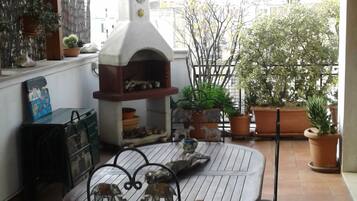Un patio al aire libre con una mesa redonda, sillas y un horno de pizza.