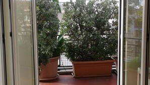 Une pièce dotée d’une porte-fenêtre coulissante donnant sur un balcon agrémenté de plantes en pot.