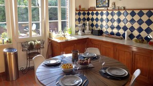 Een keuken met een eettafel voor vier personen, een spoelbak en een raam met uitzicht op groen.