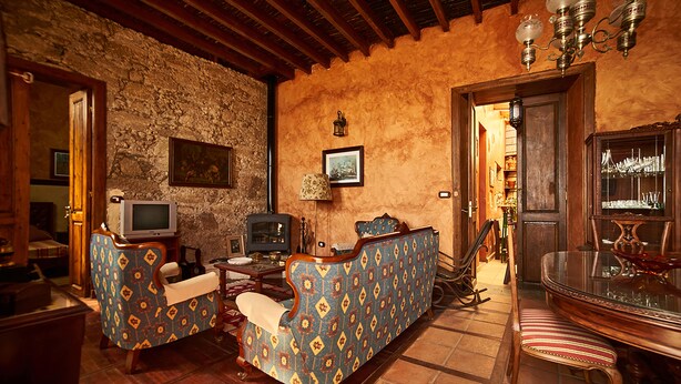 A traditional living room with a stone wall, wooden furniture, a television, and a dining area with a glass table. - Old school from (Old School from) 1840 Wifi (Fasnia)