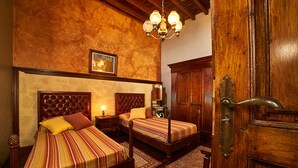 A bedroom with two beds, wooden headboards, a chandelier, and a wooden door. - Old school from (Old School from) 1840 Wifi (Fasnia)