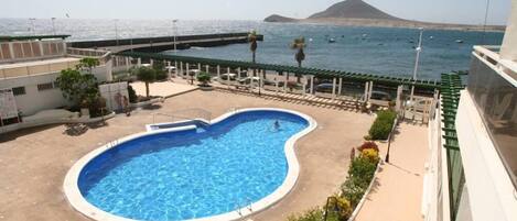 A swimming pool with a view of the sea and a mountain in the background.