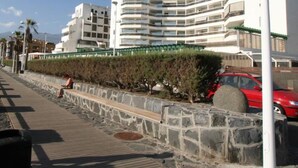 Un immeuble moderne à plusieurs étages, doté de balcons, d’un mur de soutènement en pierre et d’un chemin piétonnier pavé.