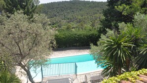 Une piscine entourée d’arbres, dans un paysage vallonné.