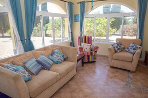 A living room with a beige sofa, a colorful armchair, and a small table.
