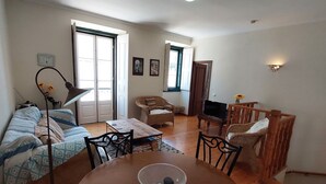 A spacious living area with a wooden dining table, chairs, a sofa, and a television. - Town House Within Lagos Castle Walls (Lagos)