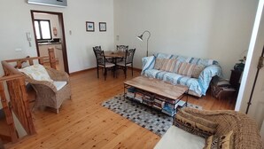 A living room with a wooden floor, a sofa, a dining table with chairs, and a bookshelf. - Town House Within Lagos Castle Walls (Lagos)