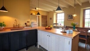 A kitchen with a central island, pendant lighting, and a view of the dining area. - Beautiful Stone Cottage - A Unique Rural Retreat In The Scottish Borders (Duns)