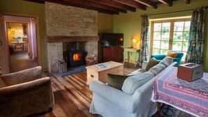 A cozy living room with a stone fireplace, wooden beams, a sofa, and a television. - Beautiful Stone Cottage - A Unique Rural Retreat In The Scottish Borders (Duns)