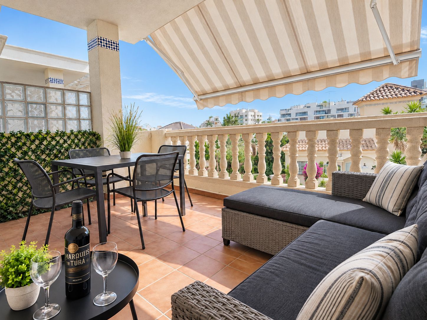 Una terrazza con tavolo, sedie, divano e una pianta in vaso.