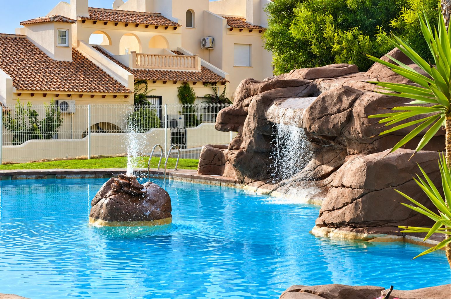 Una piscina con una formación rocosa y una cascada.