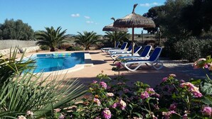 A pool area with lounge chairs and a thatched umbrella.