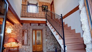 A staircase with a wooden handrail and black balusters leading to a second-floor landing with a small window.