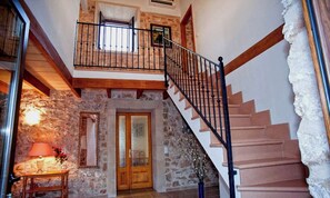 Staircase leads to an upper level, flanked by stone walls and a wooden door with glass panels.