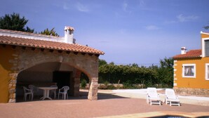 A pool area with lounge chairs and a stone building with an archway.