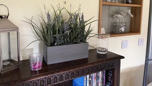Een houten plank met een bloempot, een glazen kandelaar en een metalen lantaarn.