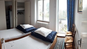 Een slaapkamer met twee bedden, een raam met uitzicht, een stoel en een radiator.
