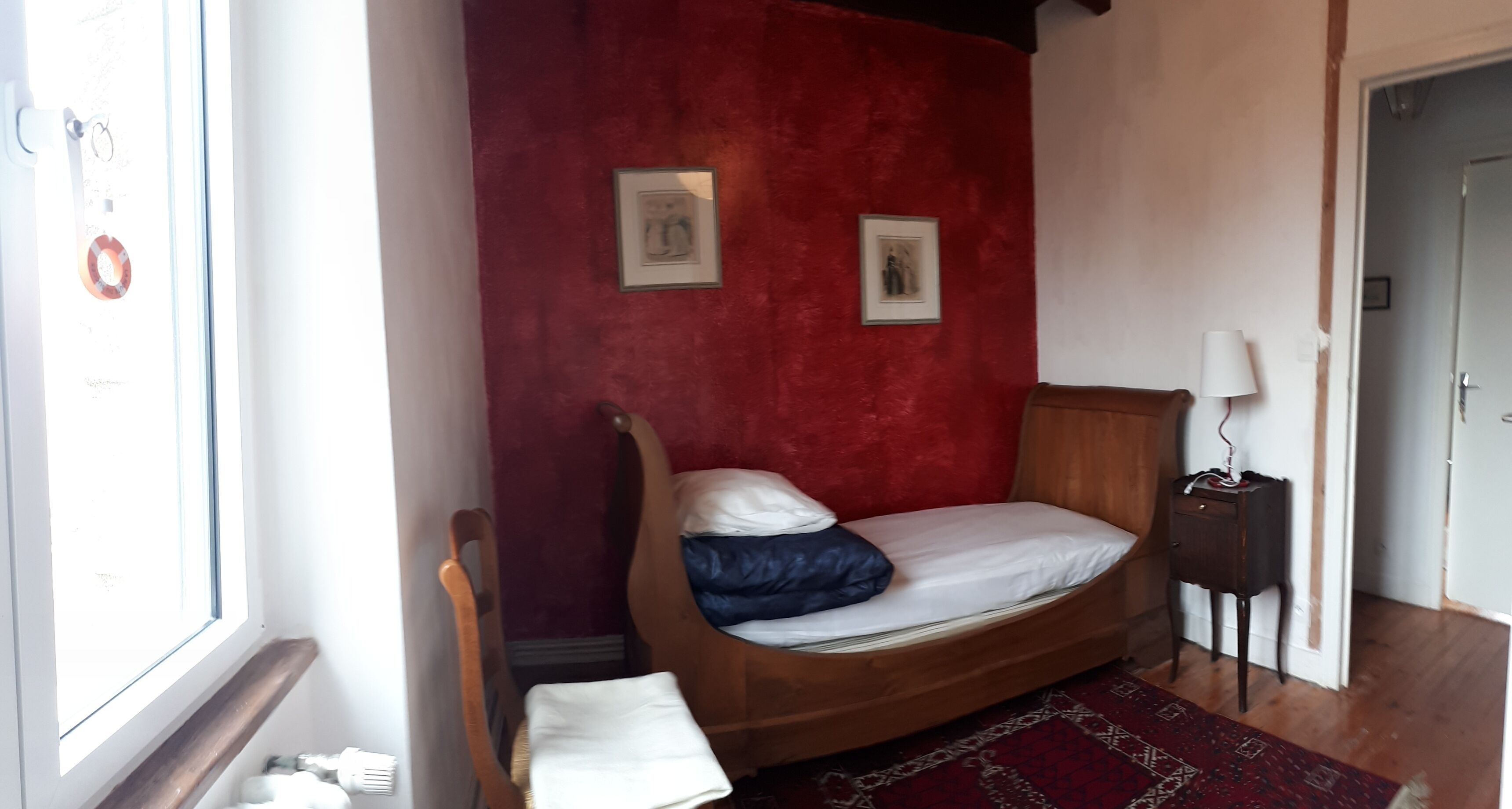 A bedroom with a wooden bed, red walls, and two framed pictures.
